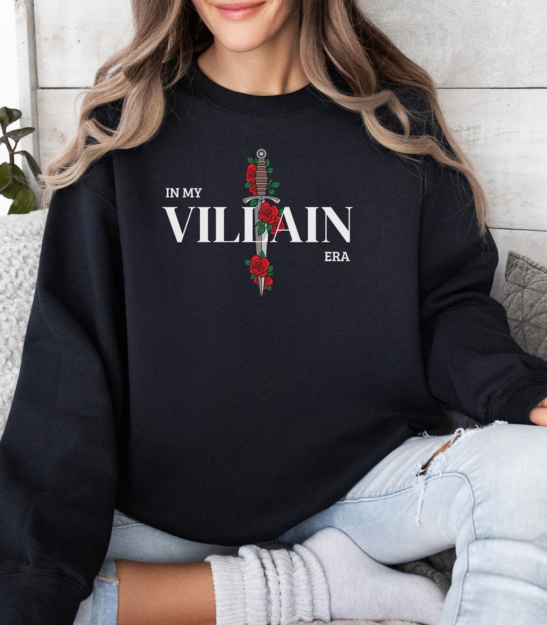 May include: Black sweatshirt with a white graphic print of a dagger with roses and the text "In My Villain Era".