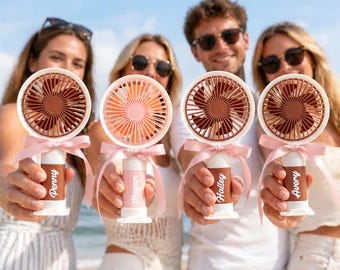 May include: Four handheld personal fans with white bases, brown fan blades, and pink ribbons. Each fan has a different name printed on the base: Penny, Megan, Hailey, and Avery. The fans are held by people on a sunny day.