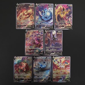 以下が含まれることがあります： 7枚のポケモンカードのコレクション。各カードには、鮮やかなアートワークとホログラフィック仕上げが施された、異なるポケモンキャラクターが描かれています。カードは暗い表面に表示され、カラフルなデザインが際立っています。