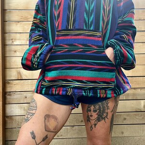 May include: A colourful striped pullover with a v-neck and a kangaroo pocket. The pullover is made of a soft, comfortable fabric and has a relaxed fit.