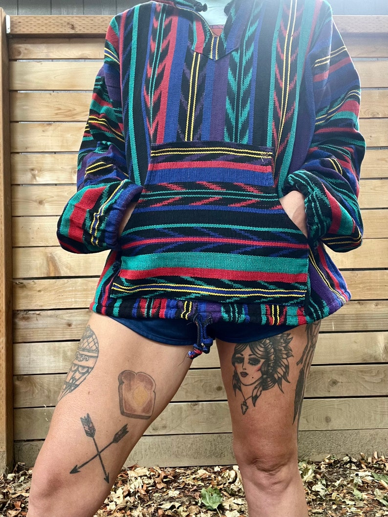 May include: A colourful striped pullover with a v-neck and a kangaroo pocket. The pullover is made of a soft, comfortable fabric and has a relaxed fit.