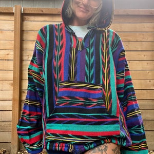 May include: A colourful striped hooded sweatshirt with a drawstring. The sweatshirt has a large pocket on the front and is made of a soft, woven fabric.
