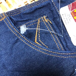 May include: A pair of dark blue denim jeans with a brown stitch detail. The jeans have a small pocket on the right side and a tag attached with the text "28" "1" "IN WAIST" "BOOT CUT" "TALL".