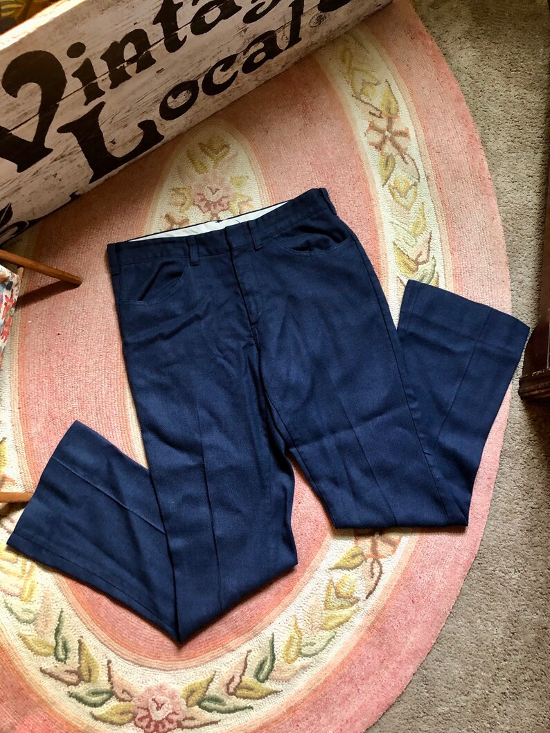 May include: A pair of dark blue, straight-leg pants with a slight flare at the bottom. The pants are made of a textured fabric and have a classic, timeless style.