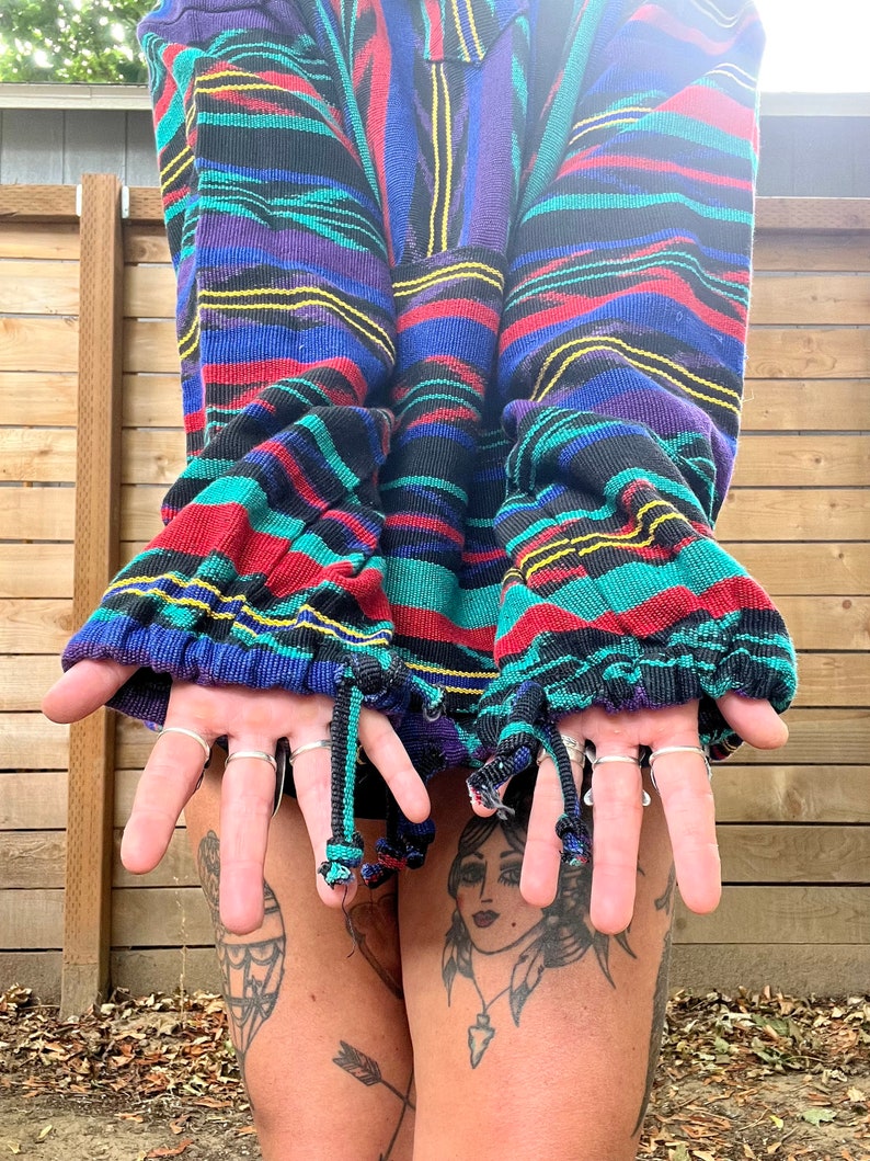 May include: A colourful striped sweater with a zip fastening and drawstring ties at the cuffs. The sweater is made from a soft, comfortable fabric and has a relaxed fit.