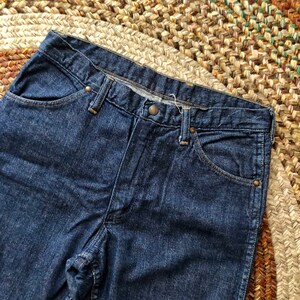 May include: A pair of dark blue denim jeans with a classic five-pocket style. The jeans have a straight leg and a relaxed fit.