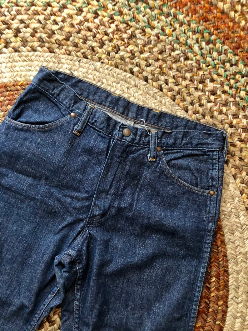 May include: A pair of dark blue denim jeans with a classic five-pocket style. The jeans have a straight leg and a relaxed fit.