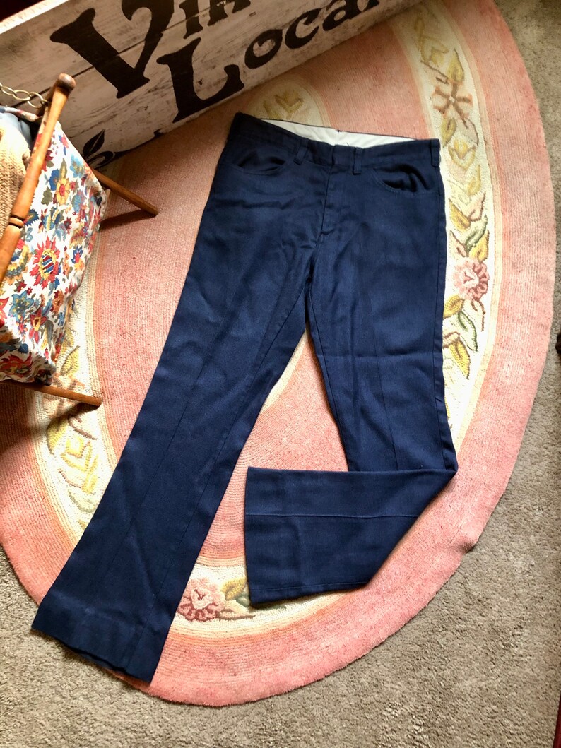May include: A pair of dark blue, straight-leg pants with a slight flare at the bottom. The pants are made of a smooth, woven fabric.
