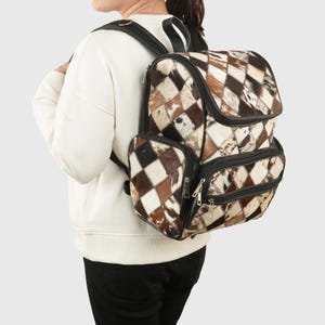 May include: A brown and white patchwork leather backpack with black accents and multiple zippered compartments.