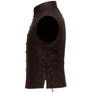 May include: A brown leather vest with a mandarin collar and gold-colored buttons. The vest has a lace-up detail on the side and a tailored fit. The vest is sleeveless and has a classic, vintage style.