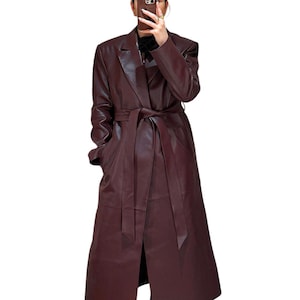 May include: A long, burgundy leather trench coat with a belt. The coat has a classic design with a lapel collar and pockets.