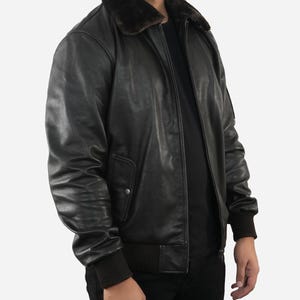 May include: Black leather bomber jacket with a brown faux fur collar. The jacket features a zip-up front, ribbed cuffs, and a ribbed hem. The jacket has a classic, timeless design.