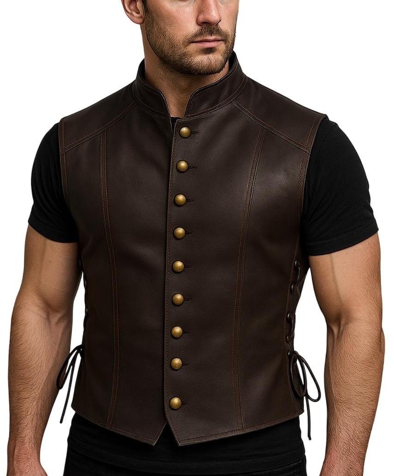 May include: A brown leather vest with a mandarin collar and gold-colored buttons. The vest has decorative stitching and side laces. The vest is a classic style.