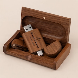 May include: A wooden USB flash drive and case. The USB drive is engraved with the names "Stacey & David" and the date "07-09-2025" along with two wedding rings. The case is open, revealing the USB drive and a small wooden piece.