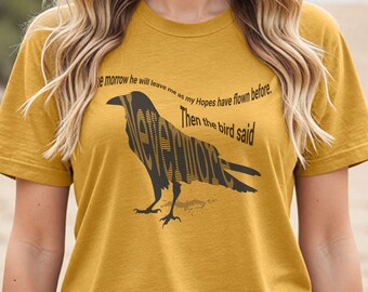 May include: A mustard yellow t-shirt with a black raven silhouette. The raven is made up of the words "Nevermore" and the text "Tomorrow he will leave me as my Hopes have flown before. Then the bird said" is printed above the raven.