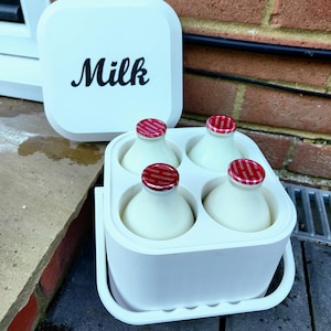Puede incluir: Un recipiente blanco con la palabra "Milk" en escritura negra en la tapa. En el interior, cuatro pequeñas botellas de leche con tapas estampadas en rojo y blanco en un soporte blanco. El soporte tiene un asa.