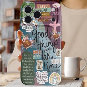 May include: A phone case with a purple, teal, and white design. The case features religious text and imagery, including a cross, a bible, and the words "Good things take time." Additional text includes "Jesus knows battles" and "Be still and know that I am God."