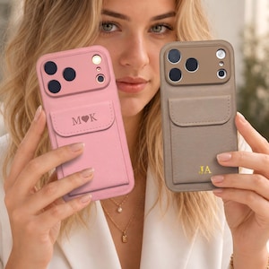 May include: Two smartphone cases with integrated card pockets. The left case is pink with the text M heart K. The right case is taupe with the gold initials JA. Both feature a raised camera housing with multiple circular lens cutouts and a flash.