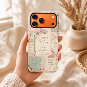 May include: A smartphone case featuring a collage design with floral patterns, butterflies, and inspirational text including Grace is Near, The Lord is with you wherever you go, Praise with joy, He restores what you've lost, and Be still and know He is good.