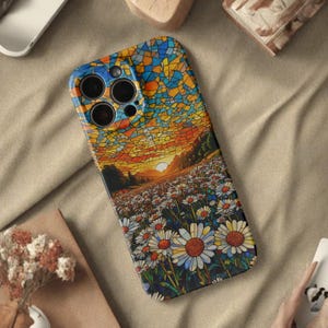 May include: A phone case with a stained-glass effect depicting a sunset over a daisy field. The design features a mosaic sky in shades of orange, yellow, and blue. The foreground shows a field of daisies with white petals and yellow centres.