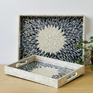 May include: Two decorative trays made of mother of pearl with a black and white geometric pattern. The larger tray is behind the smaller tray.