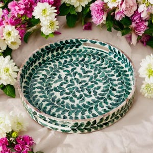 May include: A round tray with a green and white leaf pattern. The tray has a handle on one side.
