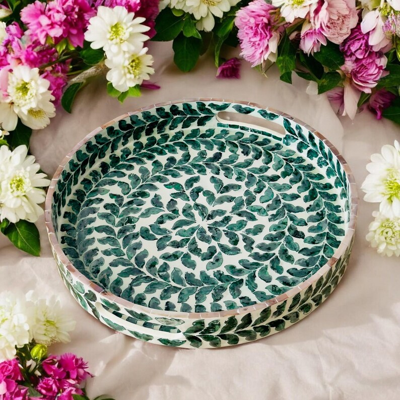 May include: A round tray with a green and white leaf pattern. The tray has a handle on one side.