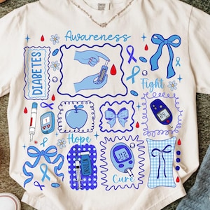 May include: White t-shirt with a blue and white graphic design related to diabetes awareness. The design includes the words "Awareness", "Diabetes", "Hope", and "Cure", along with illustrations of medical devices and symbols.