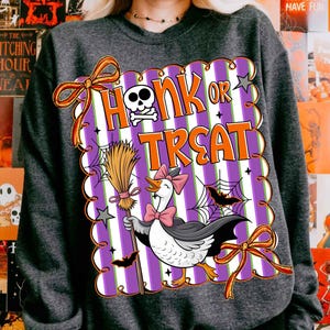 May include: Dark gray sweatshirt with a Halloween-themed graphic. The graphic features a goose wearing a bow tie and cape, holding a broom, with the words "Honk or Treat". The design includes bats, spiderwebs, and a skull.