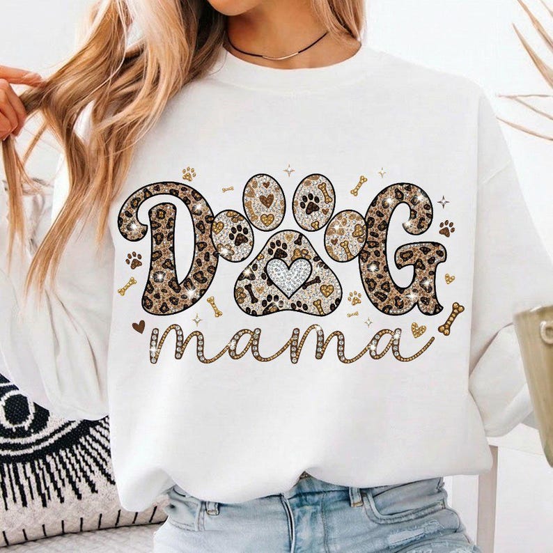 May include: White sweatshirt with the text "DOG mama" in a decorative font. The word "DOG" is in a leopard print design, with a paw print in the center. The design includes paw prints, hearts, and bones.