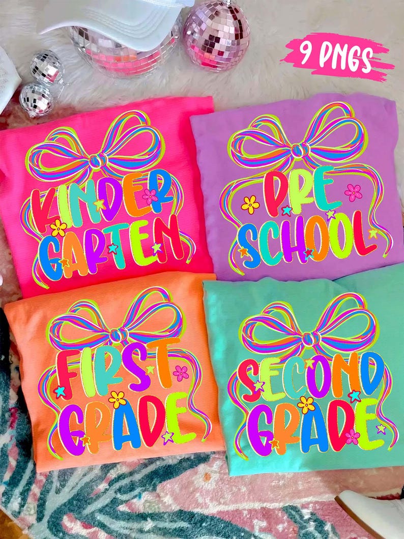 May include: Four colorful t-shirts with grade level text: Kindergarten, Pre-School, First Grade, and Second Grade. Each shirt features a large bow design and the grade level in bright, multi-colored text. The shirts are pink, purple, orange, and teal.