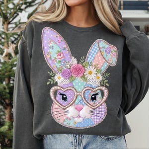 Puede incluir: Sudadera gris oscuro con un dise&ntilde;o de conejo de retazos. El conejo tiene gafas en forma de coraz&oacute;n y una corona floral. El patchwork incluye patrones rosas, morados, azules y blancos. Un estilo casual y c&oacute;modo.