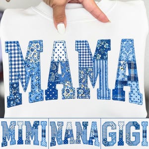 May include: White sweatshirt with the word "MAMA" in blue patchwork letters. The letters feature various blue patterns, including gingham, polka dots, and floral designs. Below, the words "MIMI", "NANA", and "GIGI" are displayed in the same style.