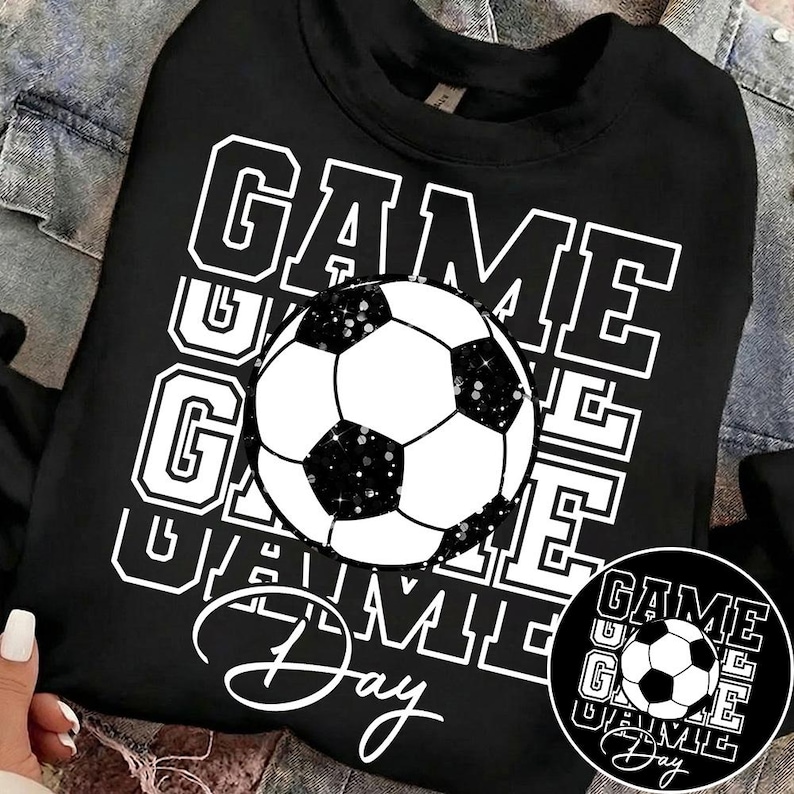 Może przedstawiać: Czarna bluza z białym nadrukiem piłki nożnej i napisem "GAME DAY" w ułożonym wzorze. Piłka nożna ma czarno-białe panele z brokatowymi akcentami. Mniejsza wersja projektu znajduje się po prawej stronie u dołu.