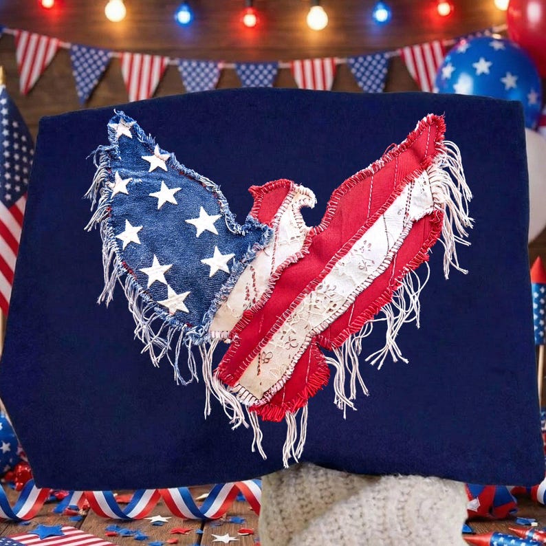 May include: A navy blue decorative pillow featuring a patriotic eagle design. The eagle is crafted from denim, red fabric, and white lace, with white stars and red and white stripes. The design has a fringed edge, evoking a vintage, handcrafted aesthetic.