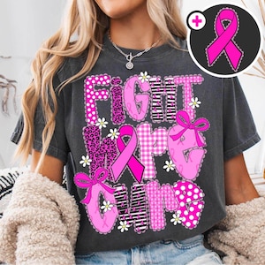 May include: Dark gray t-shirt with the words "FIGHT HOPE CURE" in pink, featuring polka dots, leopard print, gingham, and stripes. Pink ribbons and daisy accents complete the design. A pink ribbon graphic is in the upper right corner.
