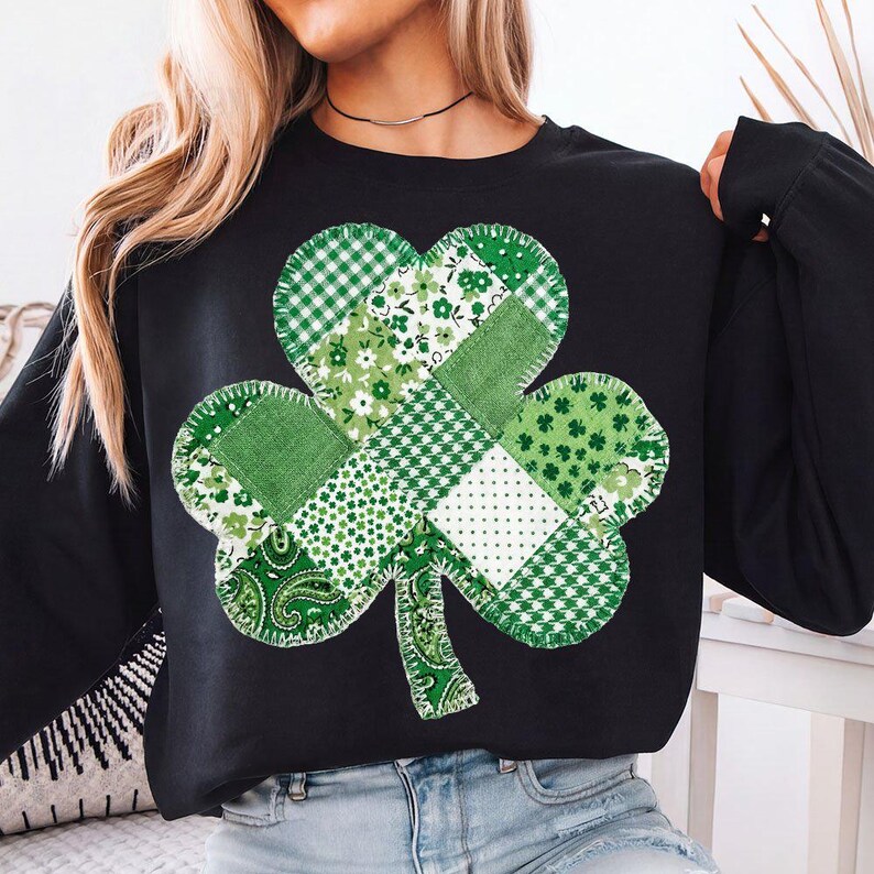 Puede incluir: Sudadera negra con un gran dise&ntilde;o de tr&eacute;bol de retazos. El tr&eacute;bol est&aacute; compuesto por varias telas verdes con estampados florales, de lunares y a cuadros. La sudadera tiene mangas largas y cuello redondo.