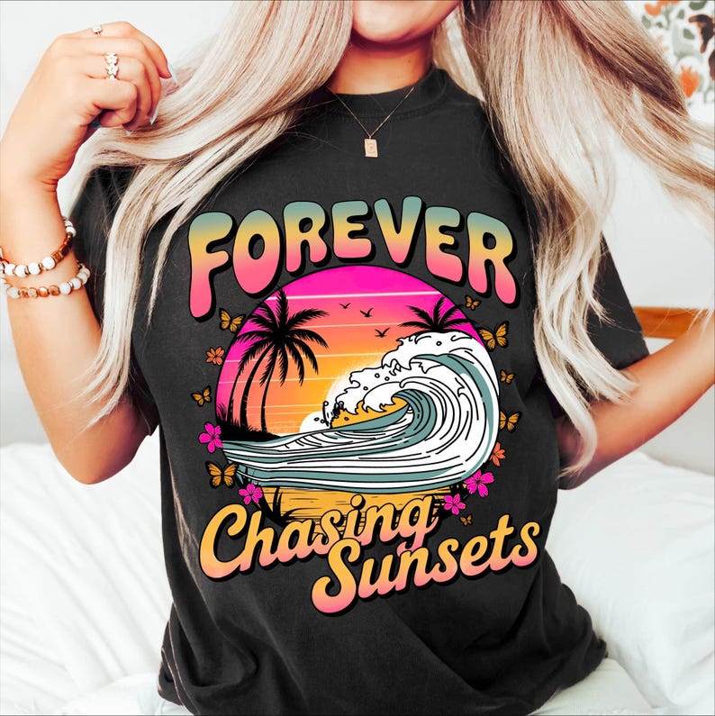 K&ouml;nnte beinhalten: Schwarzes T-Shirt mit einem farbenfrohen Grafikdesign. Das Design zeigt die W&ouml;rter "FOREVER" und "Chasing Sunsets" &uuml;ber und unter einer Sonnenuntergangsszene mit Palmen, Schmetterlingen und einer Welle.