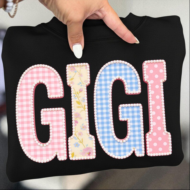 May include: Black sweatshirt with the word "GIGI" in large, colorful letters. The letters are decorated with pink gingham, floral patterns, blue gingham, and pink polka dots, outlined with small white beads.
