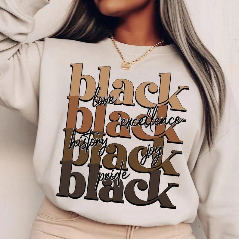 May include: Cream-colored sweatshirt with the words "black love, black excellence, black history, black joy, black pride" in brown and black lettering. The sweatshirt is a casual style.