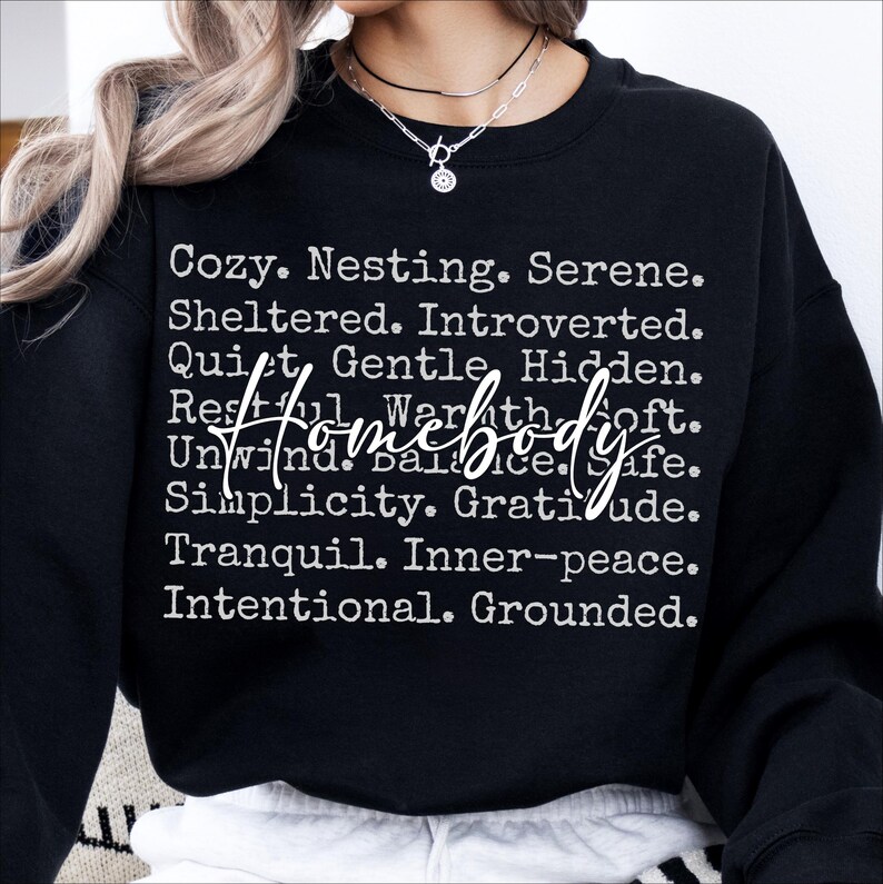 Peut inclure: Sweat-shirt noir avec du texte blanc qui dit "Cozy. Nesting. Serene. Sheltered. Introverted. Quiet. Gentle. Hidden. Restful. Warmth. Soft. Homebody. Unwind. Balance. Safe. Simplicity. Gratitude. Tranquil. Inner-peace. Intentional. Grounded."