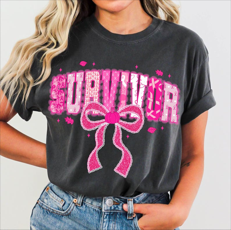 May include: Dark gray t-shirt with the word "SURVIVOR" in pink, featuring a pink ribbon bow and pink ribbon accents. The shirt is a comfortable, casual style, perfect for showing support and raising awareness.