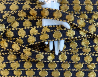 May include: Black and gold trim with a repeating pattern of gold circles. The trim is woven and has a textured look.