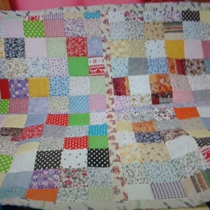 May include: A patchwork quilt made from a variety of colourful fabrics with floral, geometric and polka dot patterns.