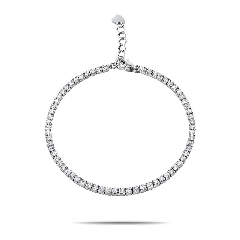 Puede incluir: Una pulsera plateada con una fila de peque&ntilde;as piedras preciosas transparentes. La pulsera tiene una cadena delicada y un detalle en forma de coraz&oacute;n cerca del cierre. Las piedras preciosas est&aacute;n espaciadas uniformemente y reflejan la luz.