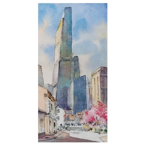 May include: A watercolor painting of a tall, dark blue skyscraper rising above a city street. The scene includes smaller buildings, a bright pink flowering tree in the foreground, and a soft blue sky. The text "heartandsupply.etsy.com" is visible.