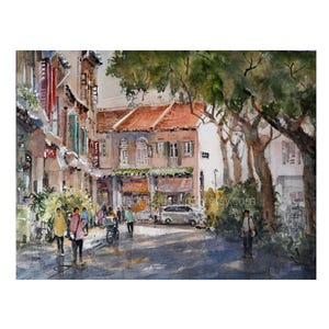 May include: A watercolor painting depicting a street scene with multi-story buildings featuring orange-tiled roofs, green shutters, and white walls. Several figures walk along the paved road, with large trees on the right and a silver car parked.