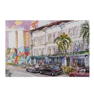 May include: A watercolor painting depicting a street scene with white colonial-style buildings, a palm tree, and parked cars. A colorful mural is visible on the side of a building. The artist's signature 'CHON' is in the bottom left corner.