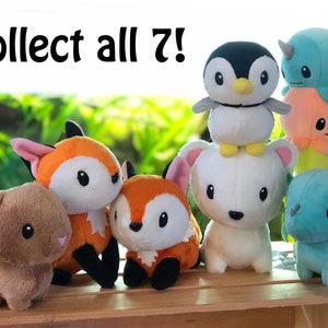 May include: A collection of seven plush toys, including a penguin, a narwhal, an octopus, a fox, a rabbit, and a dragon. The toys are all sitting on a wooden crate. The text "Collect all 7!" is written above the toys.