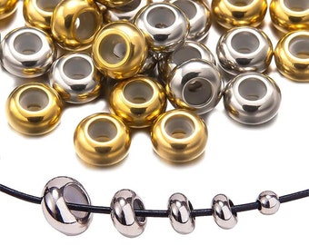 May include: A collection of gold and silver metal beads with a hole in the centre. The beads are arranged in a pile on a white surface. A necklace with three silver beads is shown at the bottom of the image.